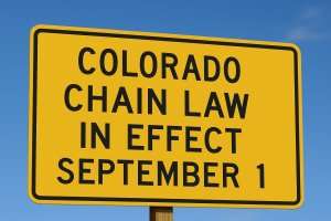 Yellow sign: “Colorado Chain Law In Effect September 1.”