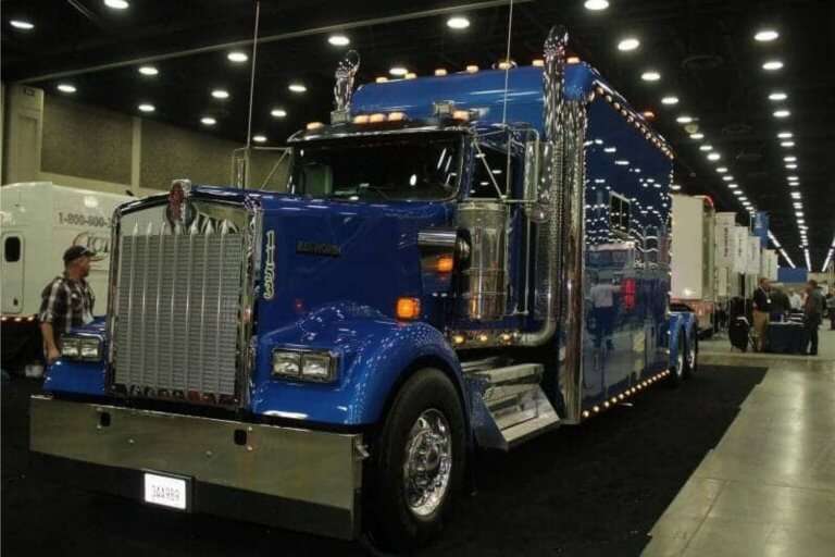 Blue Kenworth W900 show truck with chrome at indoor event.