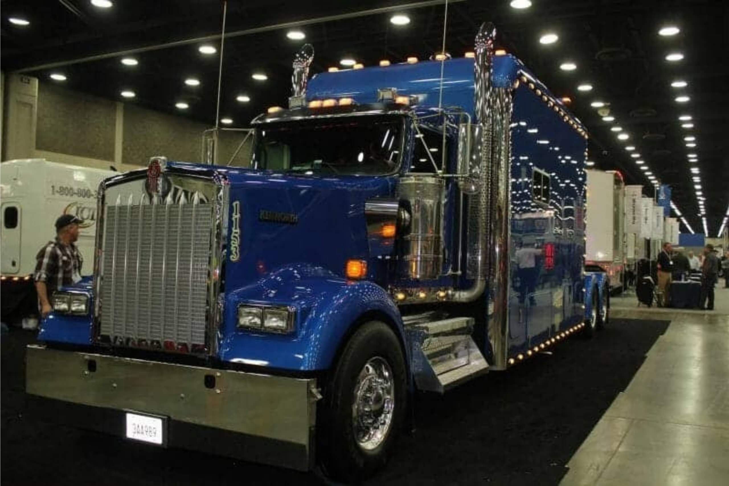 Blue Kenworth W900 show truck with chrome at indoor event.